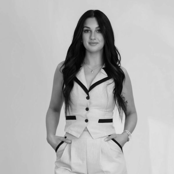 Woman in a stylish vest and pants with hands in pockets.