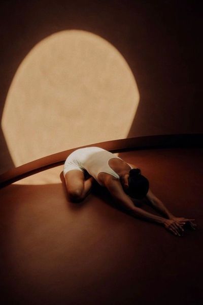 A woman resting in a gentle restorative pose in warm evening light