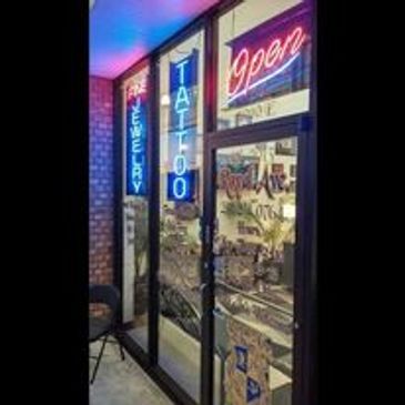 Royal Ave tattoo shops front door with neon signs saying tattoo and open