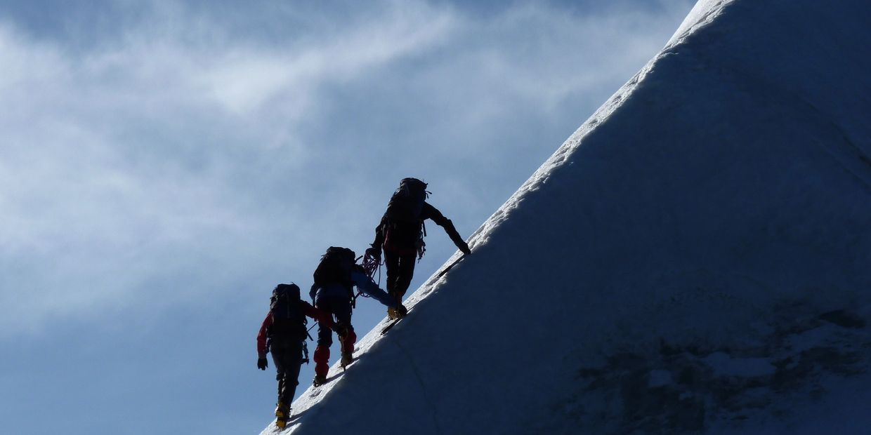 Three climbers ascending a snowy slope.