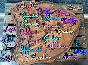 Colorful name keychains displayed on a wooden slab and pallet.