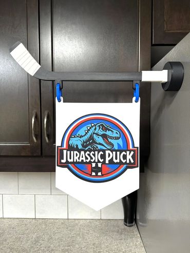 A hockey stick magnet holds a banner reading 'Jurassic Puck'.
