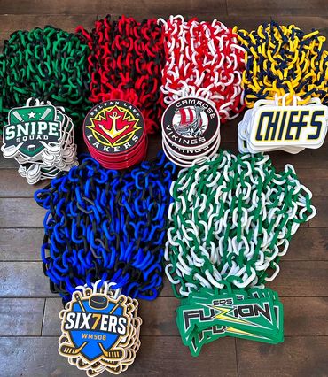 Colorful sports team medals with chains arranged on a wooden floor.