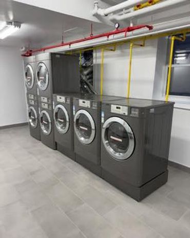 Modern laundry room with multiple front-loading washing machines and dryers.