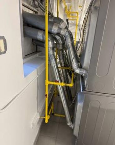 Complex ventilation pipes and yellow gas pipes installed in a utility room.