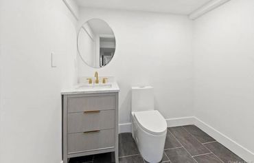 Minimalist bathroom with white walls, gray vanity, and modern toilet.