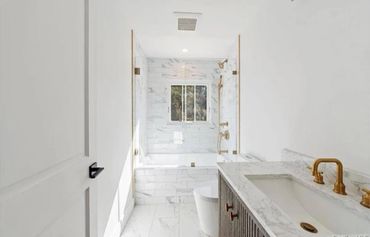 Bright modern bathroom with marble tiles and brass fixtures.