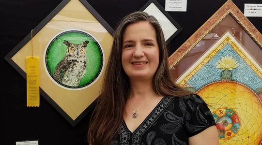 Heather next to her award winning great horned owl watercolor mandala.
