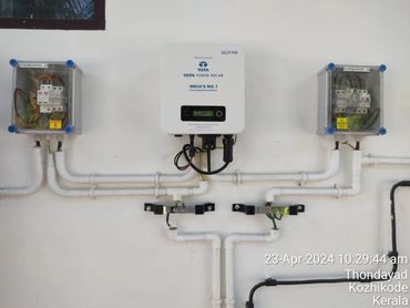 Tata Power Solar inverter setup with distribution boxes on a white wall.