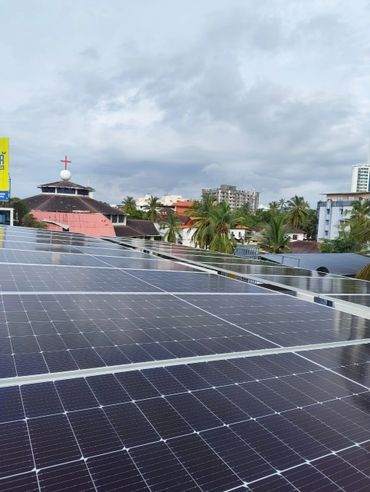 Solar panels installed on a rooftop in a city with cloudy skies.