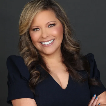 Confident woman with wavy hair smiling, arms crossed, wearing a black dress.