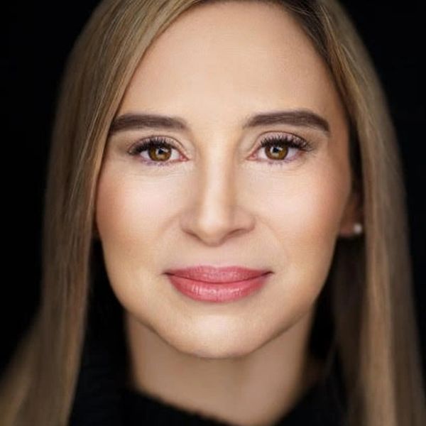 Close-up portrait of a woman with straight blonde hair and warm brown eyes.