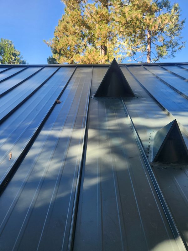 Forest green metal roof on a steep 10/12 pitch in Twain Harte, CA. Custom crickets built.