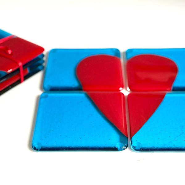 A commission piece  4 coasters in turquoise with a bright red heart made up in the middle of the 4