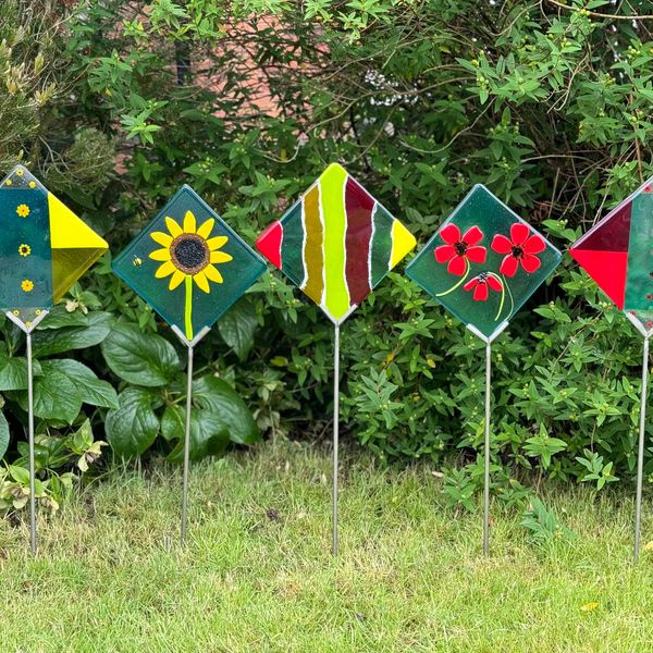 A series of 5 fused glass garden pieces in the ground flowers and bright abstract patterns