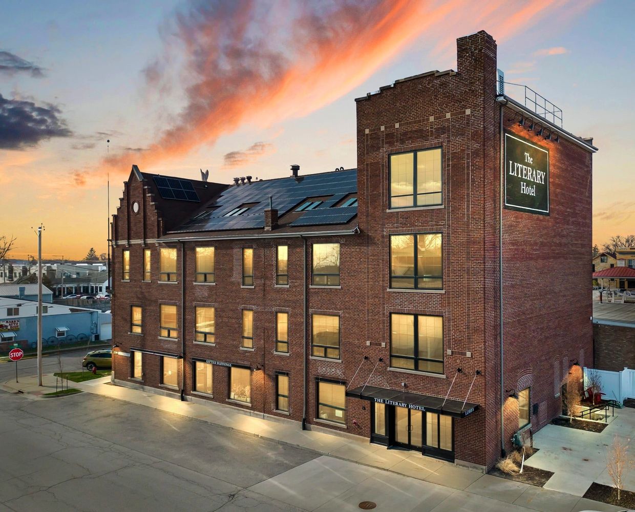 The Literary Hotel, a brick building glowing at sunset with solar panels on the roof.