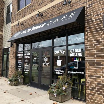 Exterior view of Good Vibes Cafe with a brick facade and black awning.