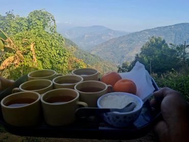 Tray of tea cups and snacks with a scenic mountain view in the background.
