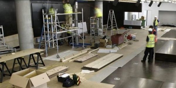 Workers assembling interior structures with scaffolding and tools.