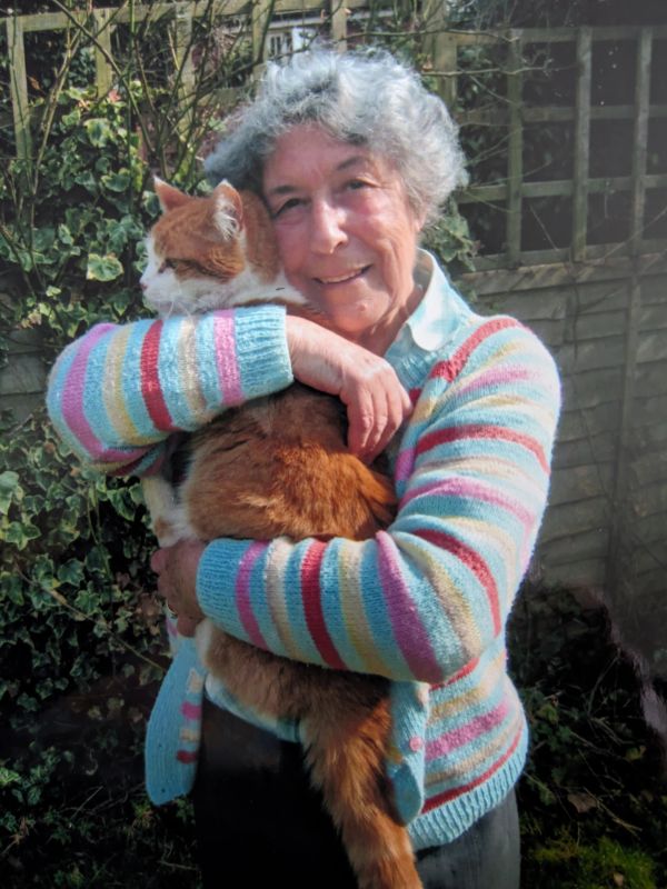 Elderly woman hugging a brown and white cat.