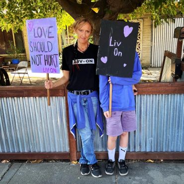 Two people holding signs advocating love and healing.