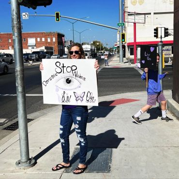 People holding signs against domestic violence on a street corner.