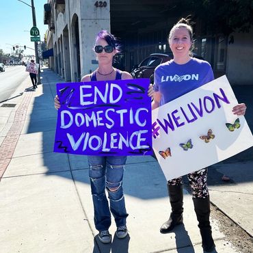 Two women hold signs advocating to end domestic violence.