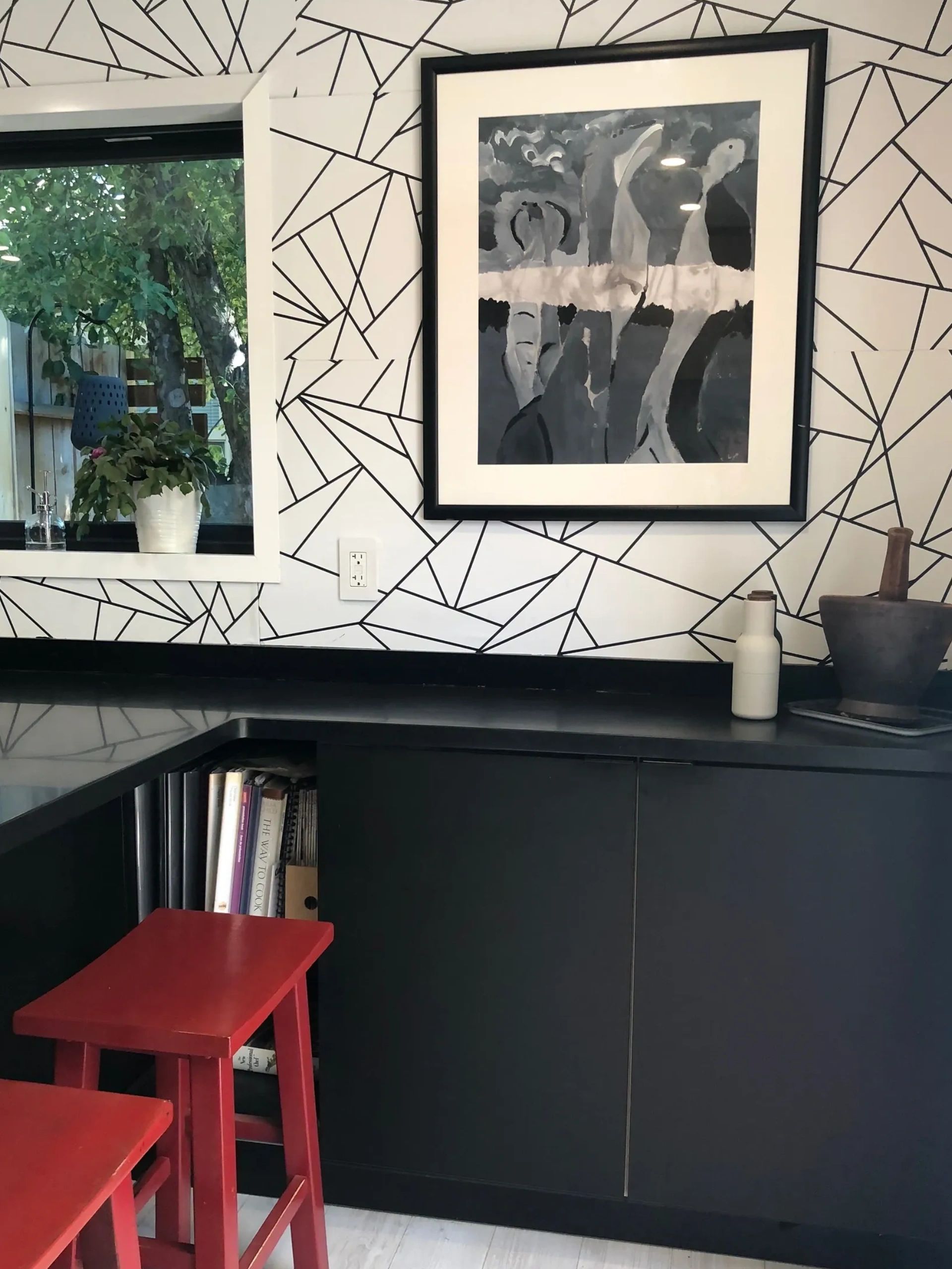 Black and white art, wallpaper and cabinetry with red stools
