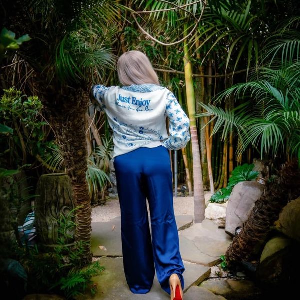 Person in blue pants and white shirt in a lush garden.