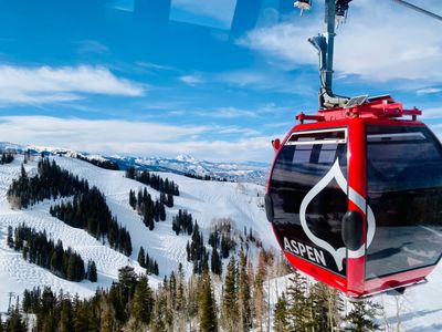 Red Aspen gondola cable car over snowy mountain slopes.