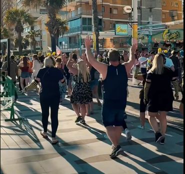 People dancing outdoors on a sunny day.