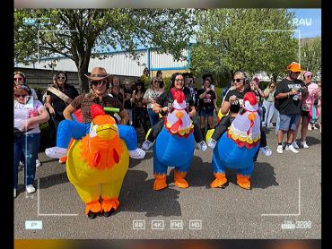 People wearing inflatable chicken costumes at an outdoor event.