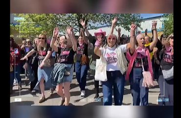 Crowd of women celebrating with hands raised outdoors.