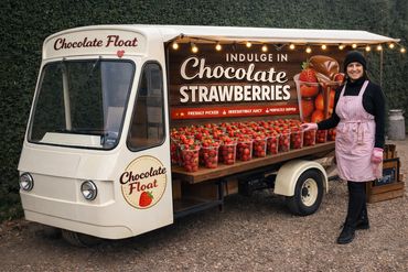 Woman selling fresh chocolate-dipped strawberries from a decorated float truck.
