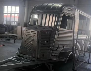 A metallic trailer shaped like a truck cab inside a workshop.