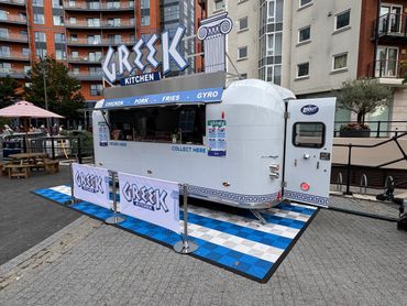 Greek Kitchen food truck in an urban setting with outdoor seating.