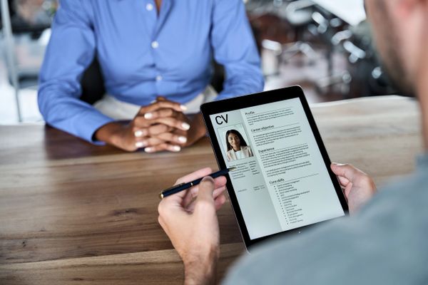 Interviewer reviews a digital CV on a tablet during a job interview.
