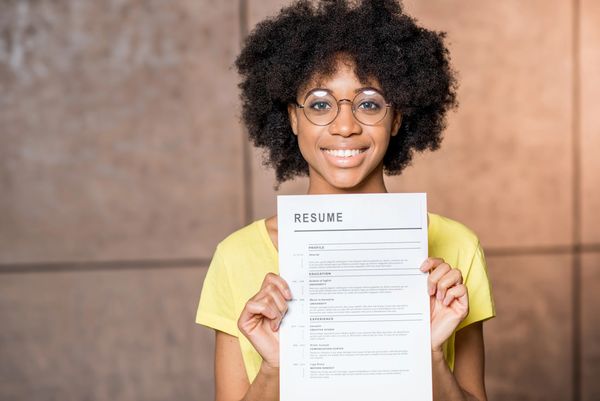 Smiling woman holding a resume, ready for job opportunities.