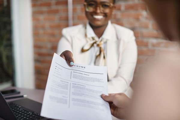 A woman hands over a resume during a job interview.