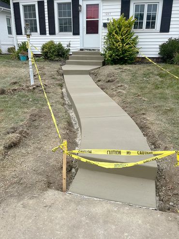 A concrete pathway and steps outside of a home.
