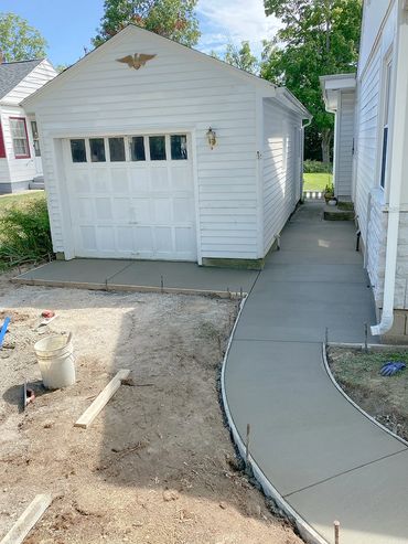 A concrete pathway around a house and garage.