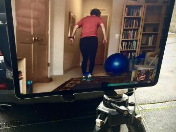 Person exercising indoors, visible on a monitor screen.