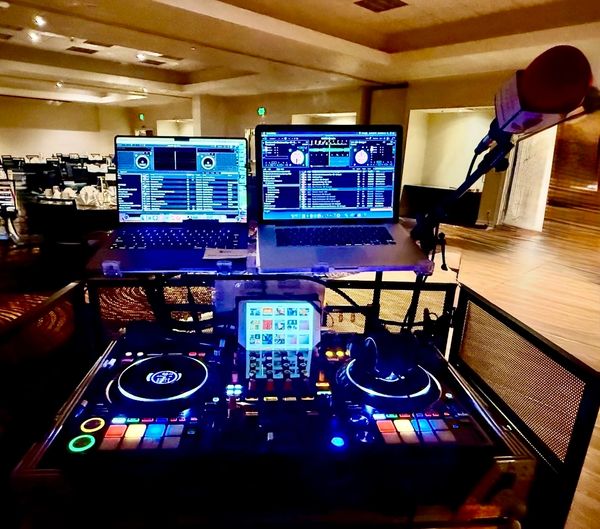 DJ setup with laptops, mixer, and microphone ready for a performance.