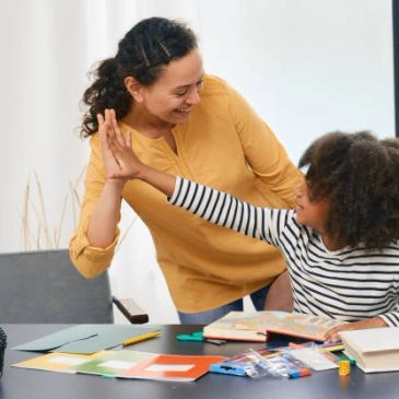 Woman and child giving a high-five while studying.