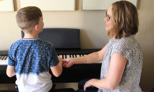 Teacher smiling at piano student.