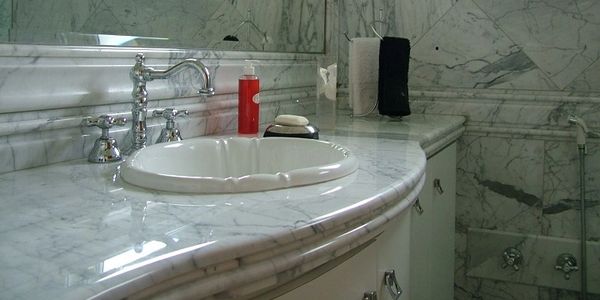Elegant marble bathroom sink with flowing water and soap.