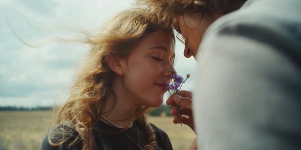 A couple sharing a tender moment smelling a wildflower.