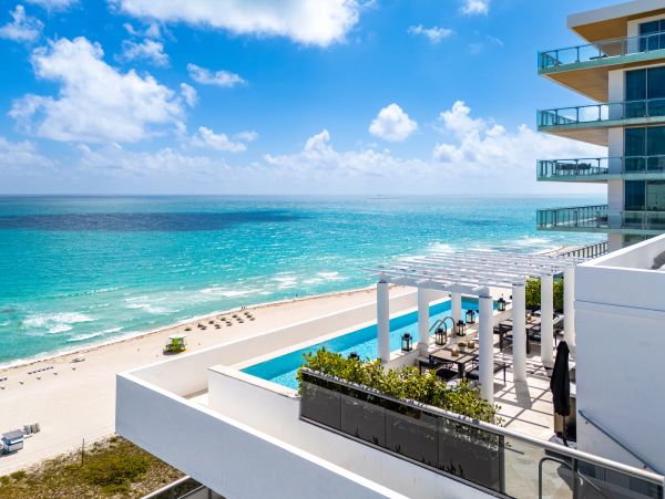 Beachfront view from a modern building with pool and ocean.