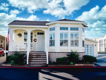 A charming house with a white porch and American flag under a bright blue sky.