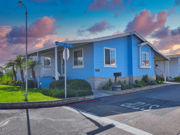 Blue house on Parrot Lane at sunset with vibrant sky.